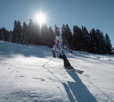 Une femme skie en bord de forêt